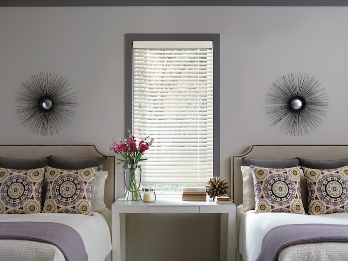 A bedroom with an upholstered headboard that has metal trim.